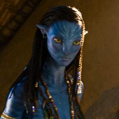 a woman with blue skin and braids standing in front of a mirror looking at the camera