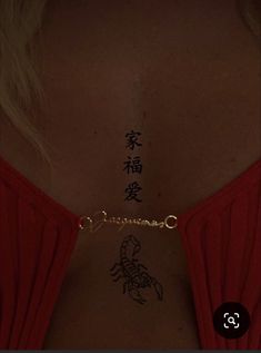 the back of a woman's neck with chinese writing on it and a scorpion tattoo