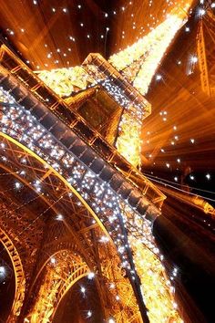 the eiffel tower lit up at night with lights on it's sides