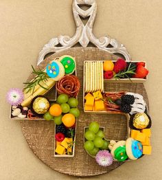 the letter f is made up of fruits and cheeses on a wooden plate with a silver frame