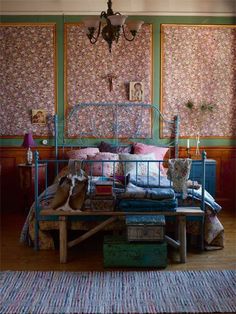 two dogs sitting on a bed in a room with floral wallpaper and rugs