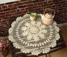 a table with a doily on it next to a potted plant and vase