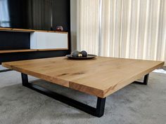 a wooden table sitting on top of a carpeted floor next to a tv stand