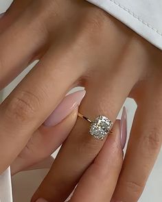 a woman's hand with a ring on top of her finger and a diamond in the middle