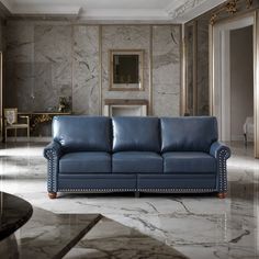 a blue leather couch sitting in the middle of a room with marble floors and walls