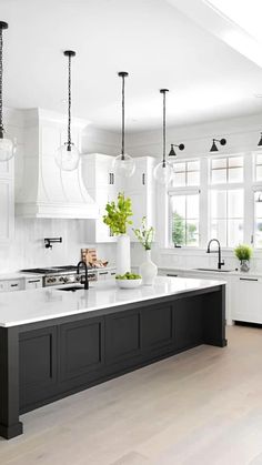 a large kitchen with white cabinets and black island