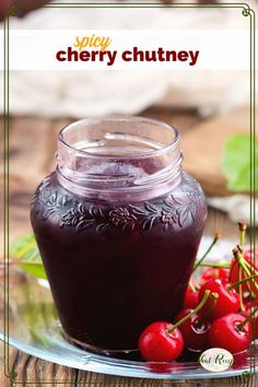 cherries sit on a plate next to a jar of cherry chutney