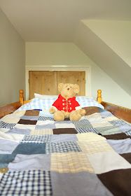 a teddy bear sitting on top of a bed in a room with slanted ceilings