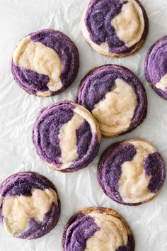 purple and white cookies with icing sitting on wax paper