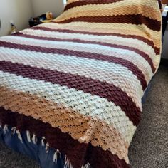 a bed covered in a multicolored blanket on top of a wooden headboard