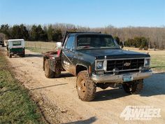 an old pick up truck is parked on the side of a dirt road next to a trailer