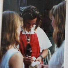 a woman in an apron is looking at her cell phone while two other women look on