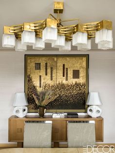 a dining room table with two chairs and a large painting on the wall behind it