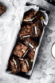 chocolate cookies with marshmallows in a pan next to a glass of milk