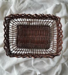 a brown basket sitting on top of a white sheet