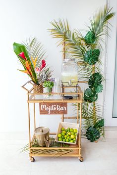 a tropical bar cart with fresh fruit and drinks on it, next to a palm tree