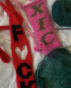 three knitted items laying on top of a bed next to a ball of yarn