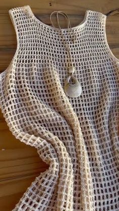 a crocheted top with a button on the front and an attached necklace hanging from it