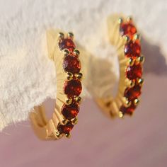 Add serious shine to your ear stack. These Garnet huggies are adorned with glistening gemstones adding a sense of royalty to your ensemble. These dainty garnet earrings hug tightly around the earlobe. Perfect for stacking with more huggies, studs or ear cuffs. Garnet is also known as January birthstones. D E T A I L S - Materials: 14k gold over sterling silver. They are 14k gold THICK plated, and they can last for a very long time with proper care. - Stone: 5 high-grade  garnet cz stones. - Inner diameter: 9mm. Outer diameter: 12mm. - Hypoallergenic, nickel, and lead-free. H O W ∙ T O ∙ O R D E R Select your gemstone in the drop-down menu.  O T H E R ∙ I N F O R M A T I O N * All items are nicely packaged and ready to gift in elegant jewelry boxes. * If you can't find the information you n Dainty Birthstone Huggie Earrings For Anniversary, Anniversary Huggie Earrings With Sparkling Stones, Dainty Gemstone Huggie Earrings In Small Hoop, Cubic Zirconia Huggie Earrings With Sparkling Stones For Gift, Gift Huggie Earrings With Sparkling Cubic Zirconia, Huggie Earrings With Birthstone In Cubic Zirconia, Cubic Zirconia Huggie Earrings With Birthstone, Huggie Earrings With Prong Setting As Gift, Hoop Earrings With Sparkling Stones For Gift