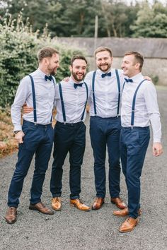 three men in blue suspenders and white shirts are standing together with their arms around each other