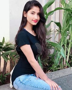 a young woman sitting on top of a cement bench next to green plants and greenery