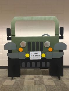 a green truck made out of cardboard sitting on top of a checkered carpeted floor