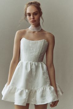 a woman in a short white dress posing for the camera with her hand on her hip