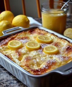 a casserole dish with lemons and powdered sugar on the side, next to two glasses of orange juice