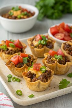 mini taco cups on a tray with tomatoes and green onion garnishes