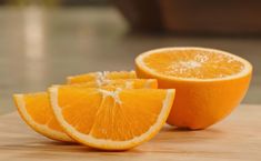 an orange cut in half sitting on top of a wooden table next to another orange