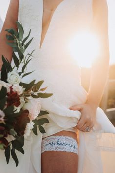 the bride is wearing her wedding garter and holding her bridal bouquet in hand