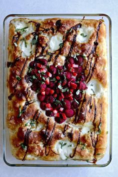 a square pastry with raspberries and cream on top is sitting in a glass dish