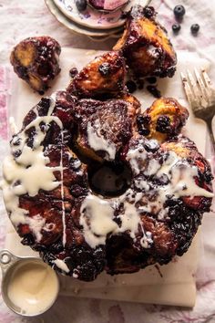 a bundt cake sitting on top of a white plate covered in icing and blueberries