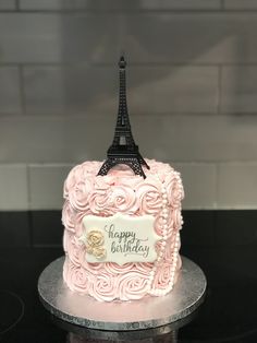 a pink birthday cake with the eiffel tower in the background