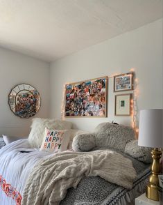 a bed with blankets and pillows on top of it next to a wall with pictures