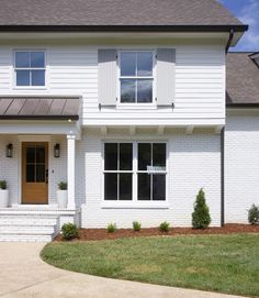 a white house with two story windows and landscaping