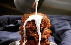 a close up of food on a plate being drizzled with white sauce