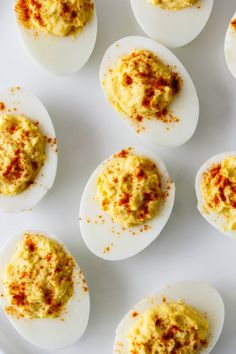 deviled eggs with mustard sprinkled on them sitting on a white platter