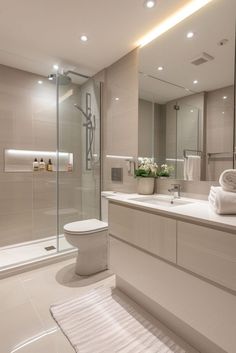 a bathroom with a sink, toilet and shower stall in the background is a white rug on the floor