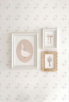 two framed pictures hang on the wall next to a shelf with flowers and birds in it