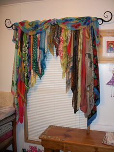 an open window covered in colorful scarves and ribbons hanging from it's side