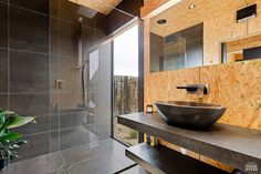 a bathroom with a large bowl sink and wooden walls in the shower area, along with a walk - in glass door