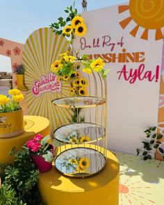 a yellow birdcage filled with flowers sitting on top of a table next to potted plants