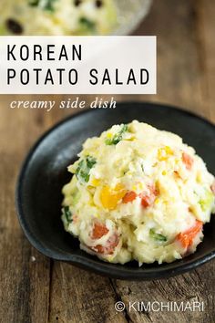 korean potato salad with fuji apples and cucumbers in a black bowl on a wooden table