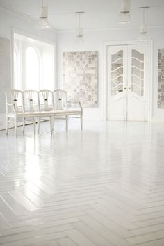 an empty room with chairs and tables in the center, white walls and flooring