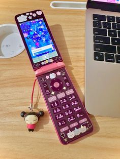 a cell phone sitting on top of a wooden table next to a laptop computer and keychain