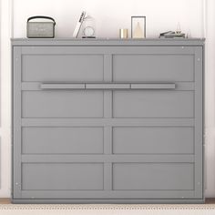 a gray dresser sitting in the corner of a room next to a clock and other items