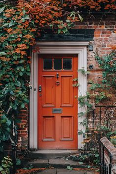 an orange front door surrounded by greenery