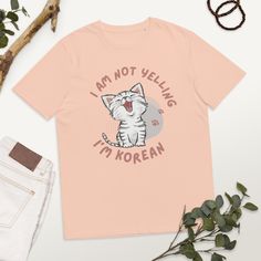 "Made from 100% organic ring-spun cotton, this unisex t-shirt is a total must-have. It's high-quality, super comfy, and best of all--eco-friendly. The \"I am not yelling I'm Korean\" t-shirt is a funny and lighthearted way to show off your pride and love for Korean culture. This shirt is perfect for anyone who is a fan of Korean food, music, fashion, or just loves the country itself. The shirt features a bold and humorous message that is sure to catch people's attention. It is a great conversation starter and a way to show off your unique personality. This t-shirt makes for a great gift for anyone who loves Korean culture. It is perfect for birthdays, holidays, or any special occasion. The shirt is available in a variety of sizes and colors, so you can choose the one that best fits your st Pink Organic Cotton Short Sleeve T-shirt, Pink Short Sleeve Organic Cotton T-shirt, Pink Organic Cotton T-shirt With Graphic Print, Spring Cotton T-shirt With Funny Text, Korean Culture, Polish Ideas, Organic Ring, K Drama, Great Conversation Starters