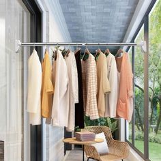 an outdoor room with clothes hanging on the rail and a chair in front of it